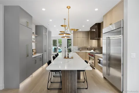 a kitchen with stainless steel appliances kitchen island granite countertop a refrigerator a stove a kitchen island with a dining table and chairs