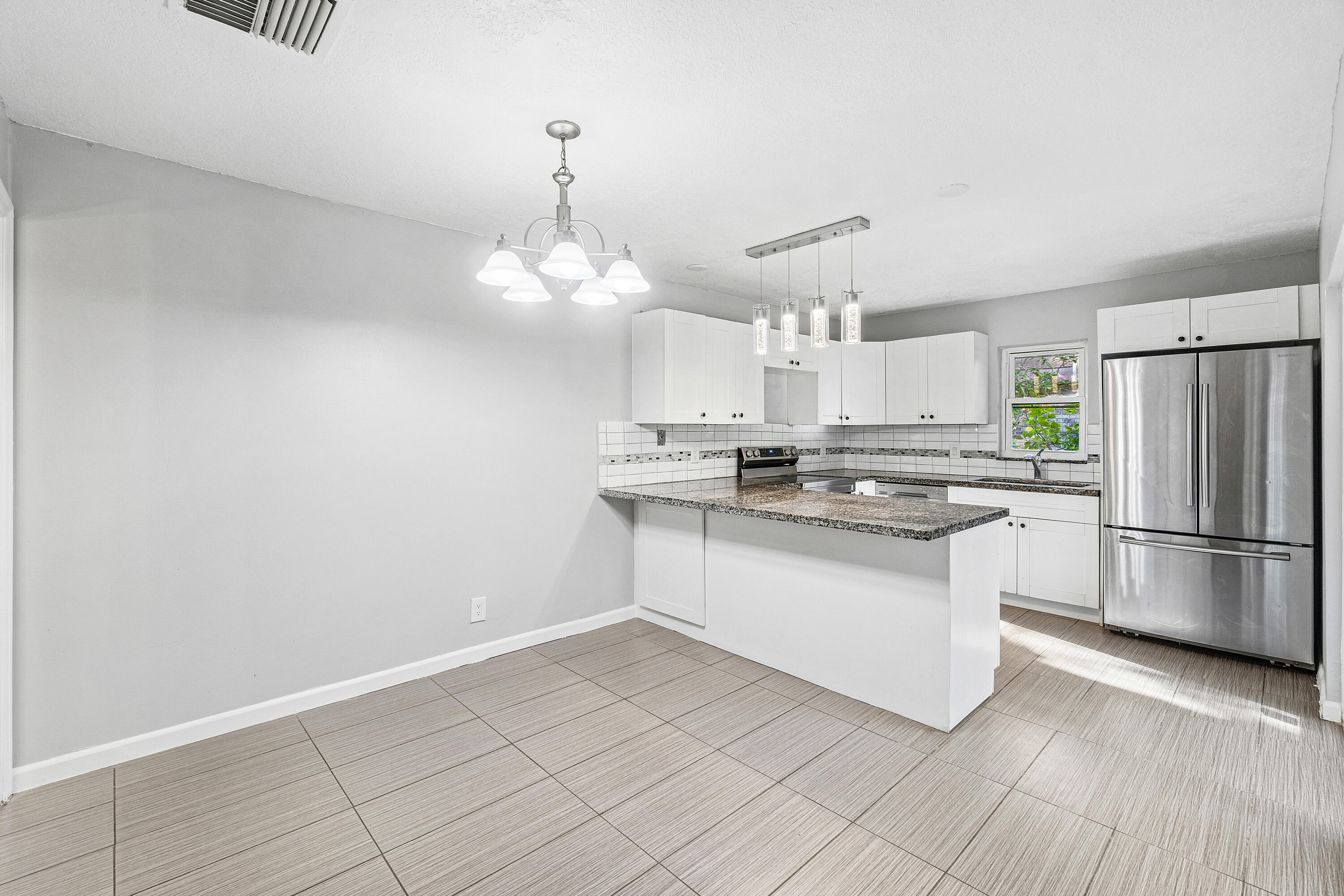 7536 Courtyard Run East Boca Raton, FL 33433 - Photo 8 of 25 a kitchen with kitchen island granite countertop a refrigerator a stove a oven and white cabinets with wooden floor