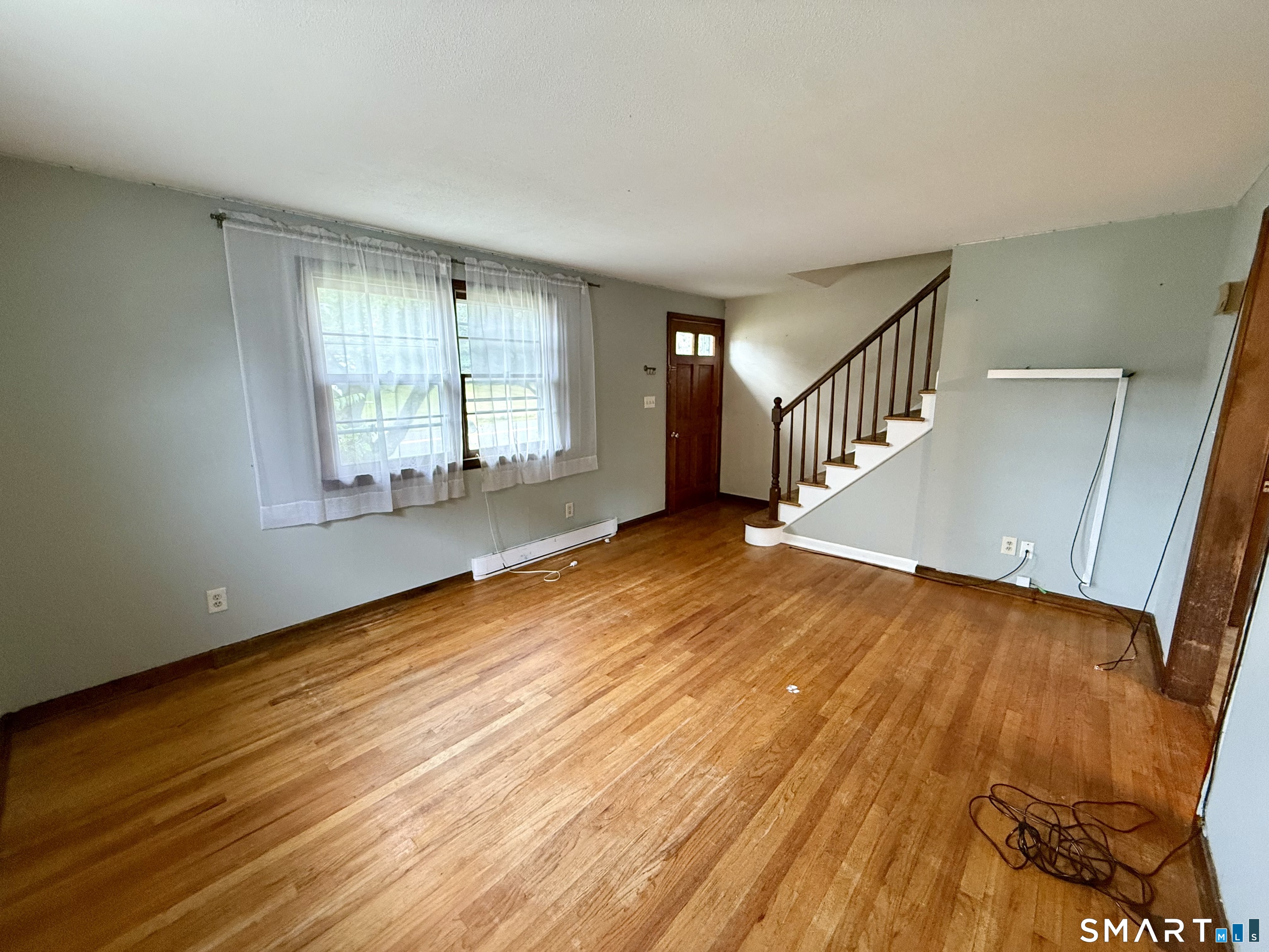 a view of an empty room with wooden floor and a window