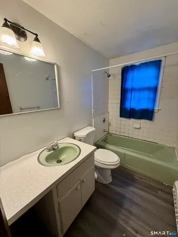 a bathroom with a granite countertop toilet sink and mirror