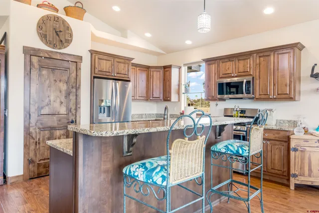 a kitchen with granite countertop a stove a sink a dining table and chairs