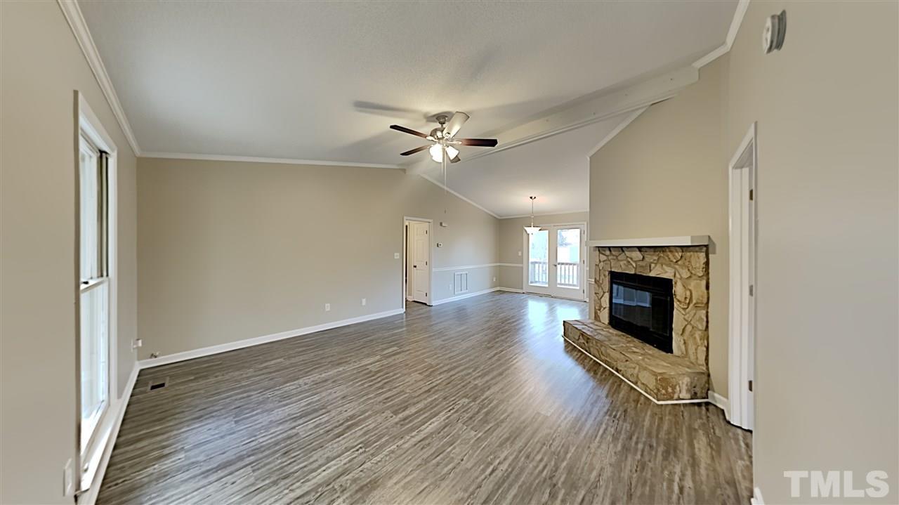4225 Labrador Drive Raleigh, NC 27616 - Photo 3 of 13 an empty room with wooden floor a fireplace and windows