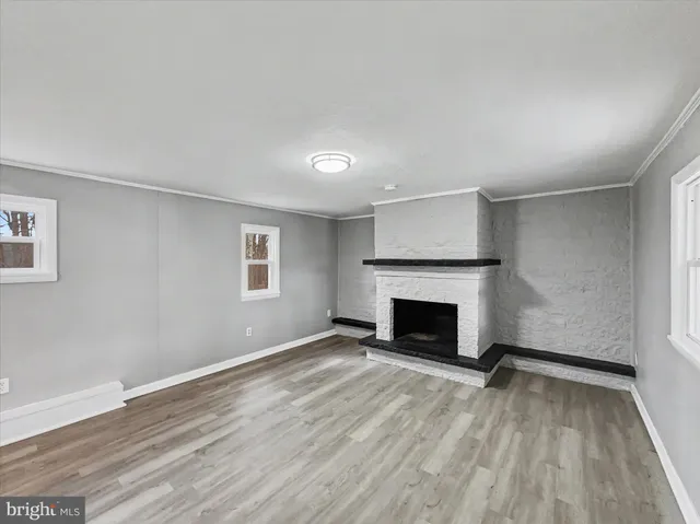 an empty room with wooden floor fireplace and windows