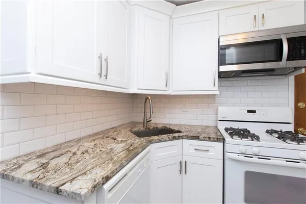 a kitchen with granite countertop white cabinets and stainless steel appliances