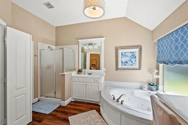 a bathroom with a double vanity sink a mirror a bathtub and next to a window