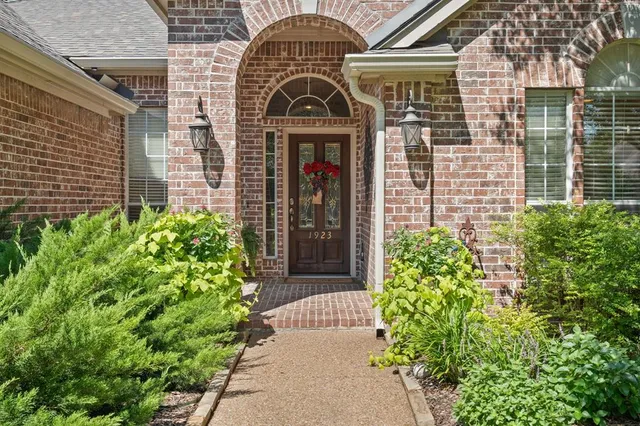 front view of a brick house with a large window and potted plants