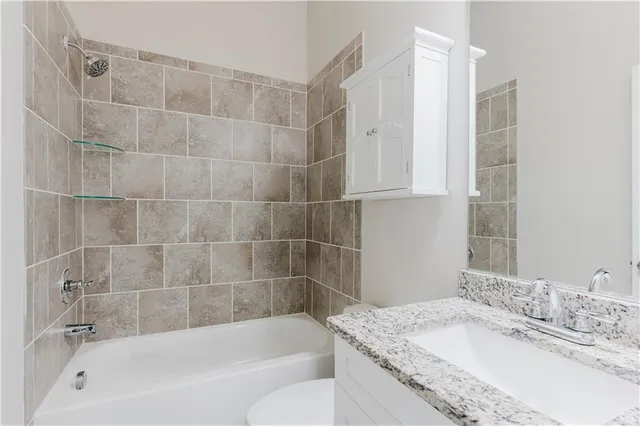 a bathroom with a granite countertop bathtub shower sink and vanity