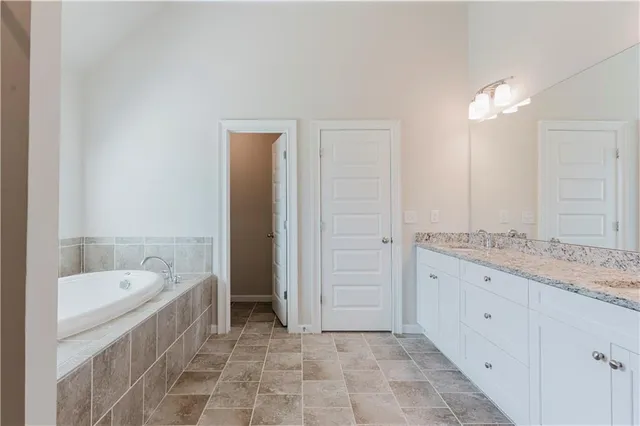 a bathroom with a granite countertop sink a large mirror and a bathtub