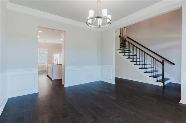 a view of an empty room with wooden floor and a chandelier