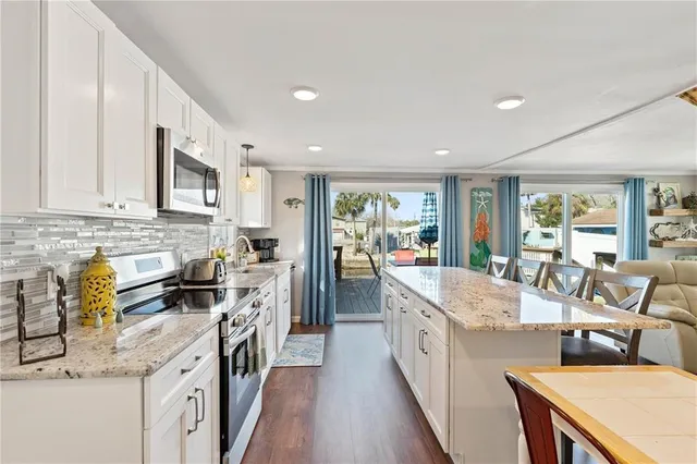 a large kitchen with stainless steel appliances granite countertop a lot of counter space and wooden floors