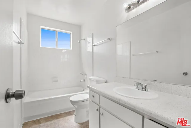 a bathroom with a granite countertop sink a toilet and shower
