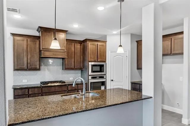 a kitchen with stainless steel appliances granite countertop a refrigerator a sink and a stove