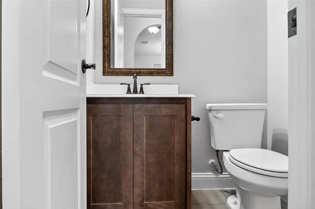 a bathroom with a granite countertop toilet sink and mirror