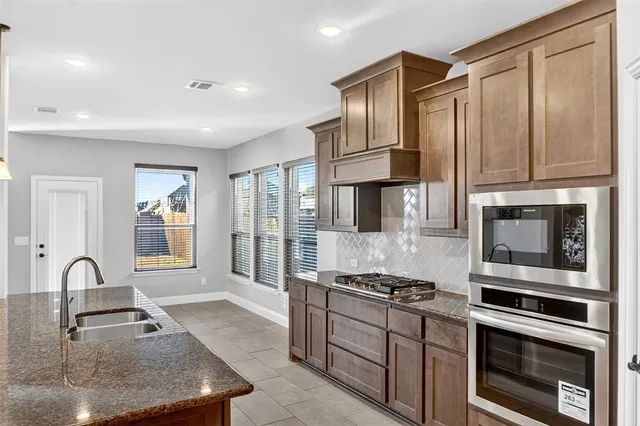 a kitchen with stainless steel appliances granite countertop a stove a sink and a microwave