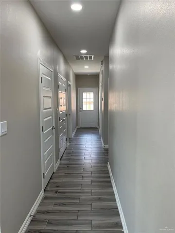 a view of an empty room with wooden floor and a window