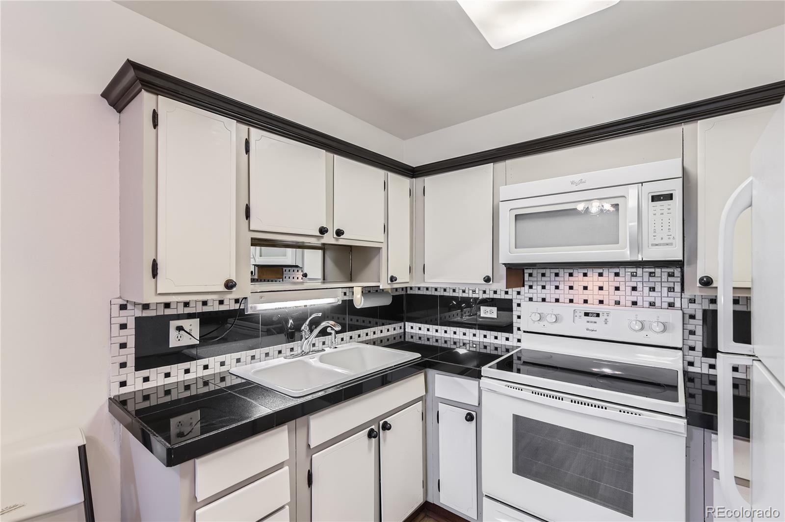 735 South Clinton Street, Unit 5B Denver, CO 80247 - Photo 4 of 15 a kitchen with granite countertop a stove sink and cabinets