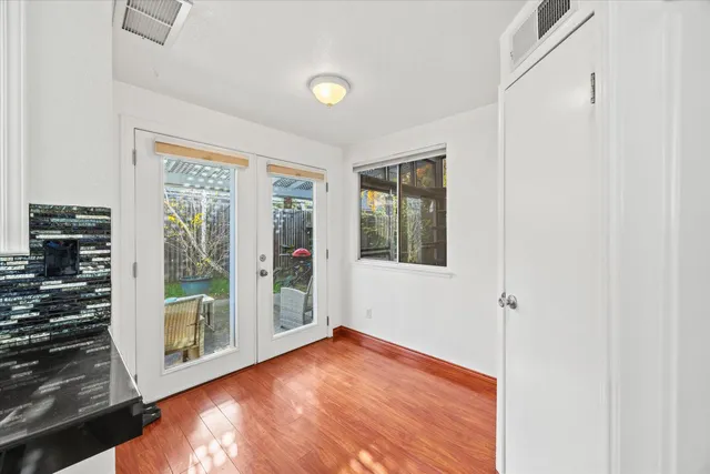 a view of an empty room with a window and wooden floor