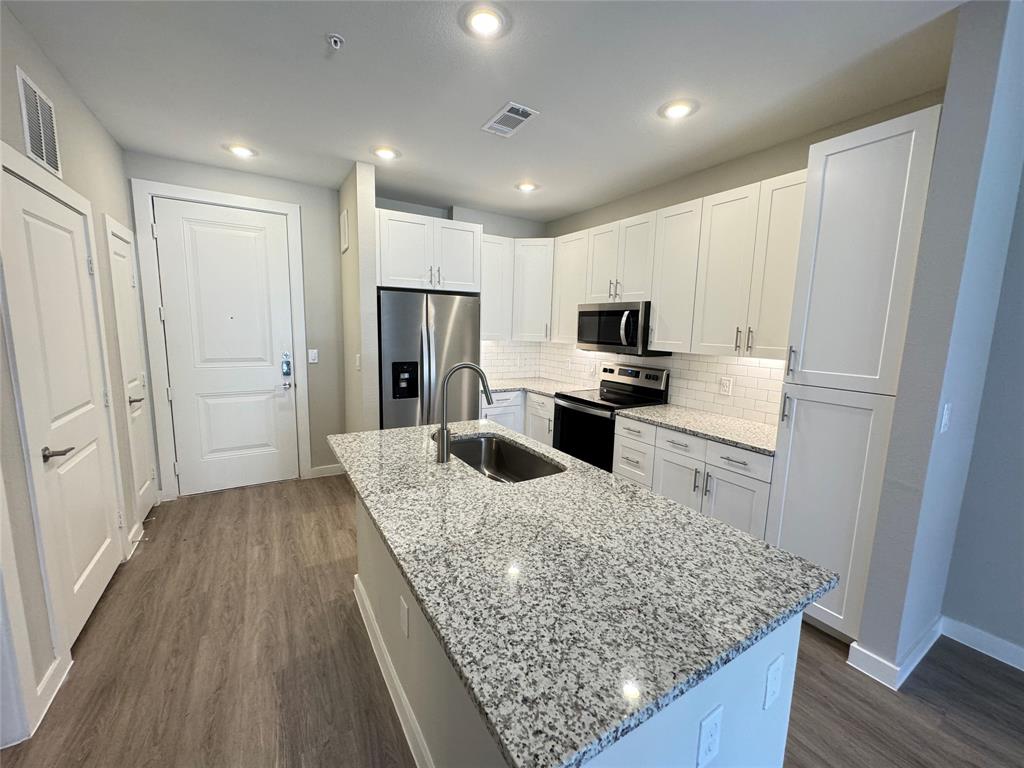 a kitchen with granite countertop wooden cabinets a refrigerator and a sink