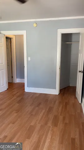 a view of an empty room with wooden floor and closet