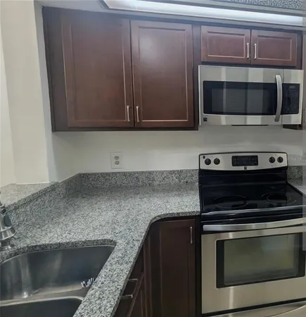 a kitchen with granite countertop stainless steel appliances a stove microwave and sink