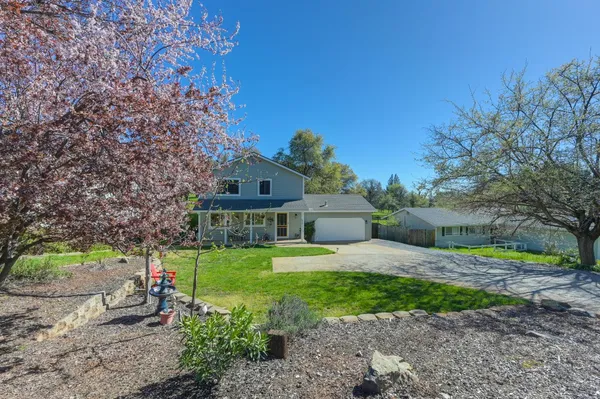 a front view of a house with a yard and trees