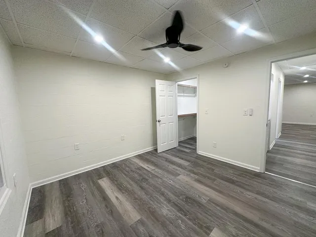 an empty room with wooden floor and ceiling fan