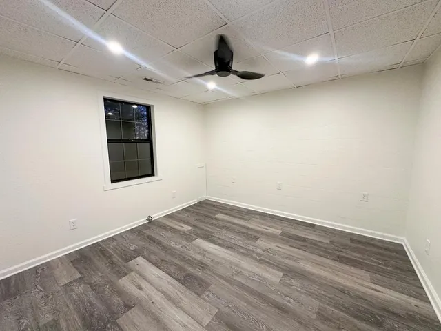 an empty room with wooden floor ceiling fan and windows