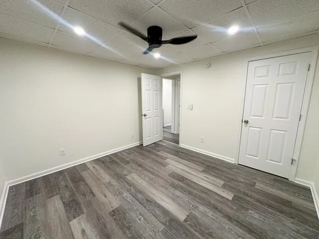 an empty room with wooden floor and ceiling fan