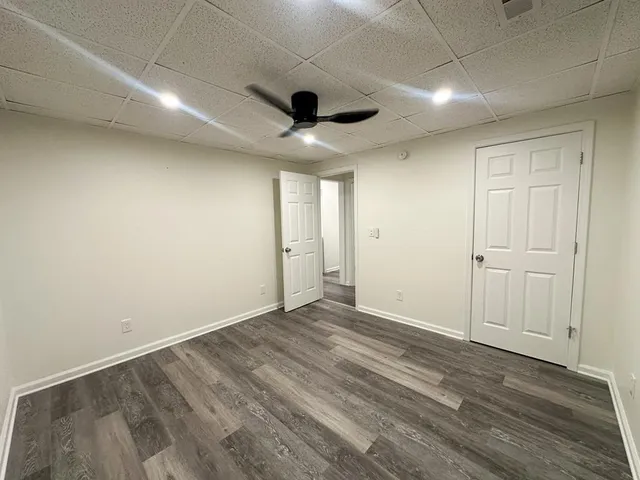an empty room with wooden floor and a ceiling fan