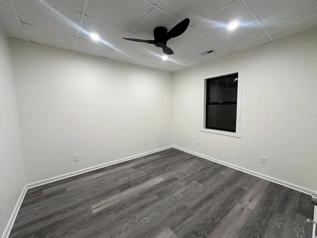 an empty room with wooden floor and ceiling fan