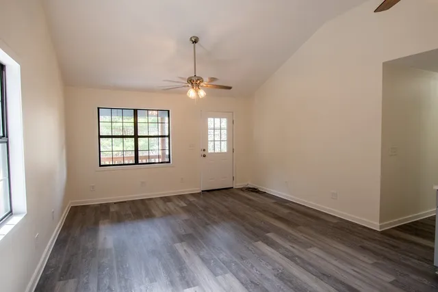 an empty room with wooden floor chandelier and windows
