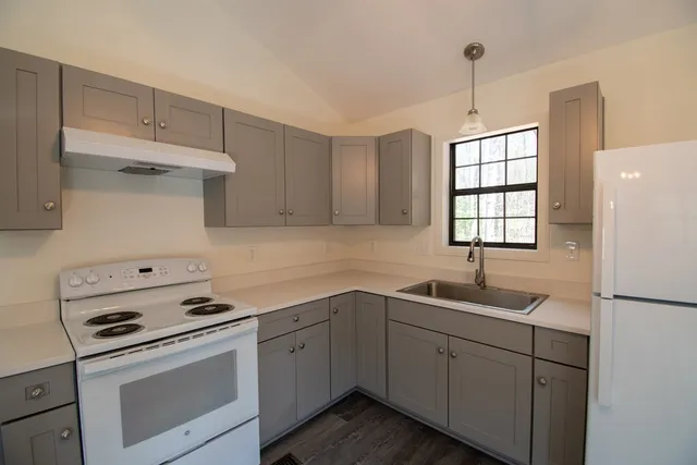 a kitchen with cabinets appliances a sink and a window