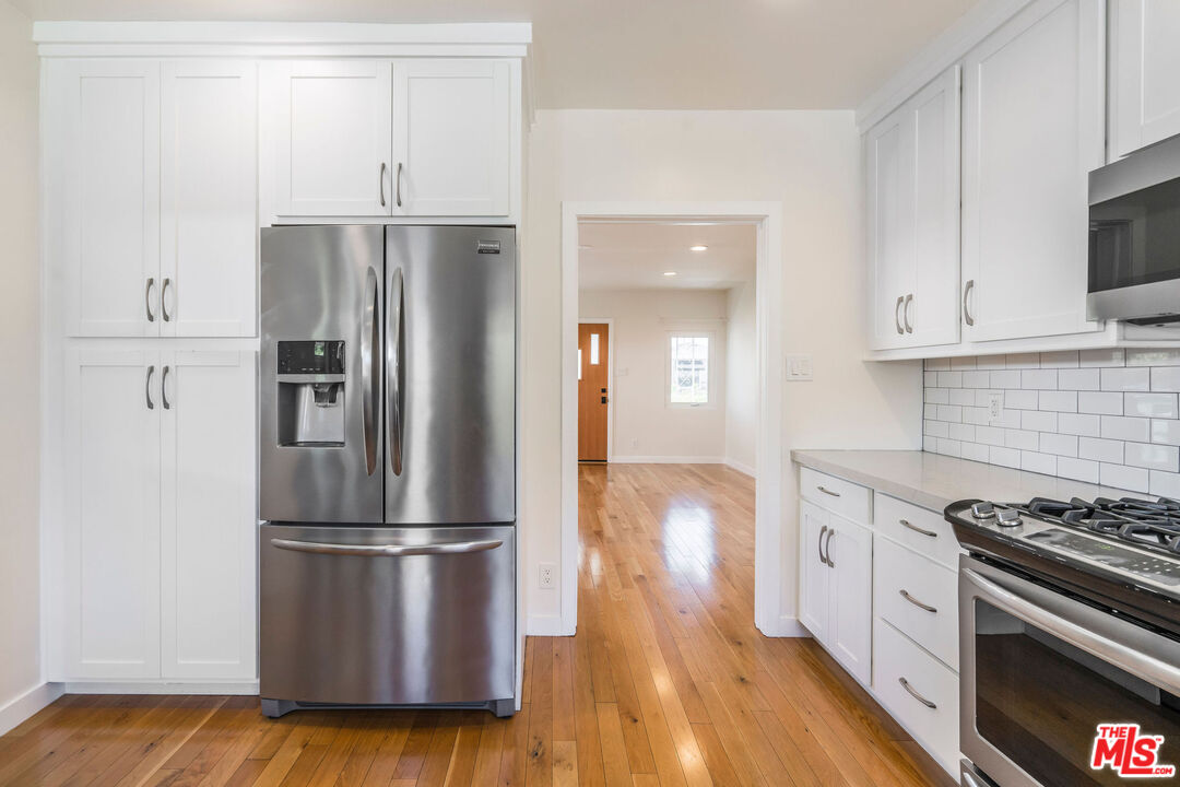 1215 North Avon Street Burbank, CA 91505 - Photo 12 of 37 a kitchen with stainless steel appliances wooden floor sink and stove