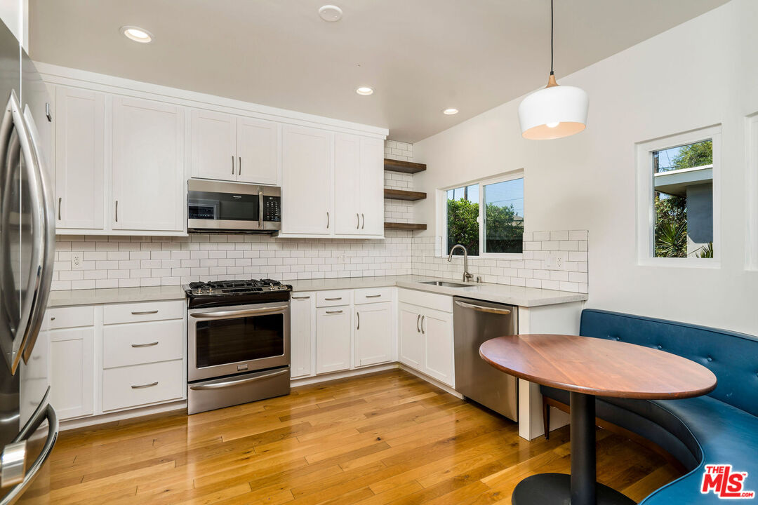 1215 North Avon Street Burbank, CA 91505 - Photo 10 of 37 a kitchen with stainless steel appliances kitchen island granite countertop a stove a sink and a microwave