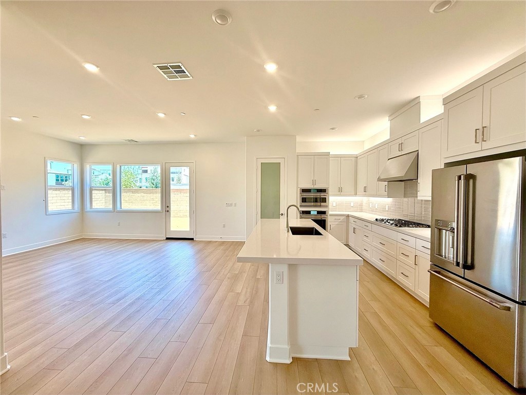a large kitchen with stainless steel appliances lots of counter top space and wooden floor