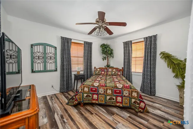 a bedroom with a bed a dresser and potted plants