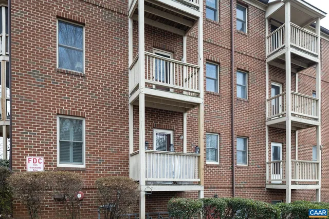 a front view of a brick building next to a yard