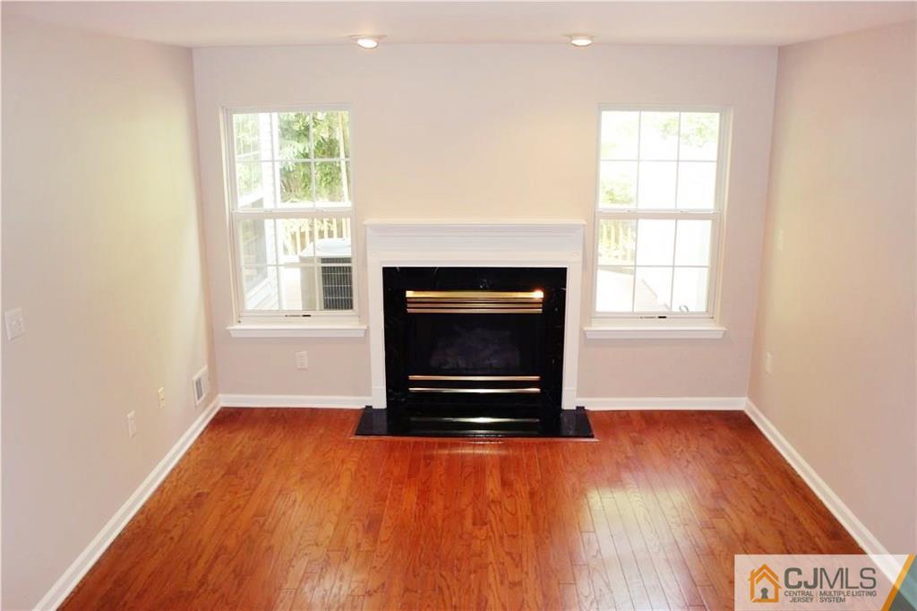 43 Alpine Road Holmdel, NJ 07733 - Photo 5 of 25 an empty room with wooden floor a fireplace and windows