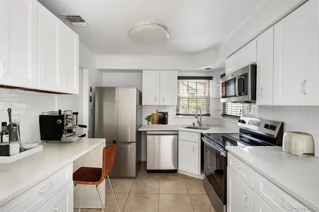 a kitchen with granite countertop a sink a counter top space stainless steel appliances and cabinets