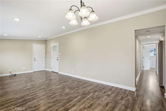 a view of an empty room with wooden floor and a large window