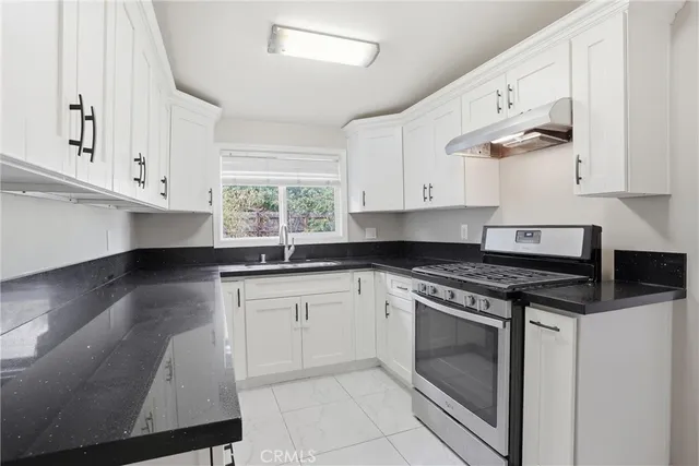 a kitchen with granite countertop white cabinets stainless steel appliances and a window