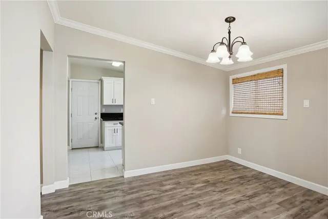 an empty room with wooden floor chandelier and windows