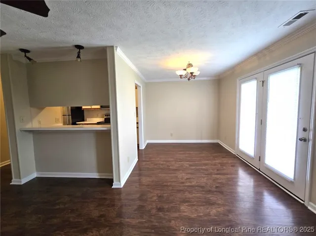 a view of an empty room with window and wooden floor