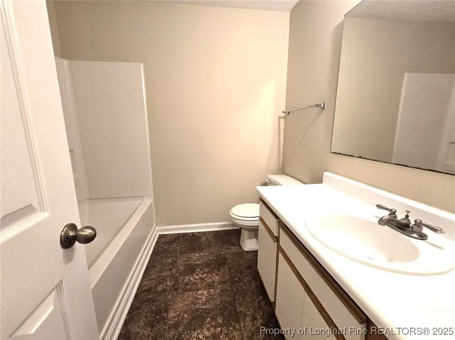a bathroom with a granite countertop toilet and a bathtub