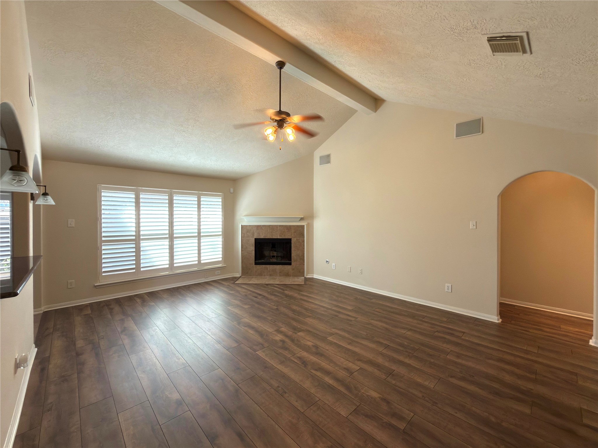 13102 Castlewind Lane Pearland, TX 77584 - Photo 2 of 31 Bright, freshly updated living room featuring brand-new flooring, new interior paint, beautiful wood shutters, a cozy corner fireplace, and a wall of windows that fills the space with natural light.