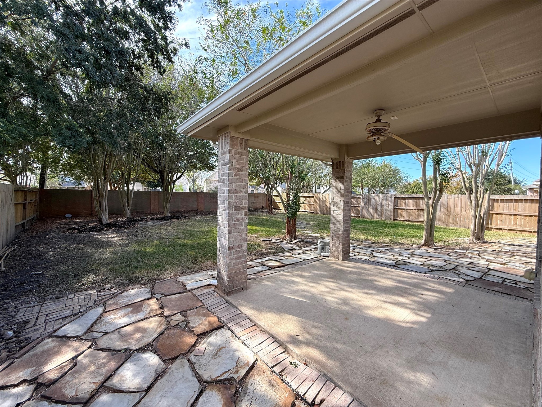 13102 Castlewind Lane Pearland, TX 77584 - Photo 29 of 31 Spacious covered patio, perfect for outdoor relaxation and entertaining. Stone accents and mature trees create a peaceful setting.