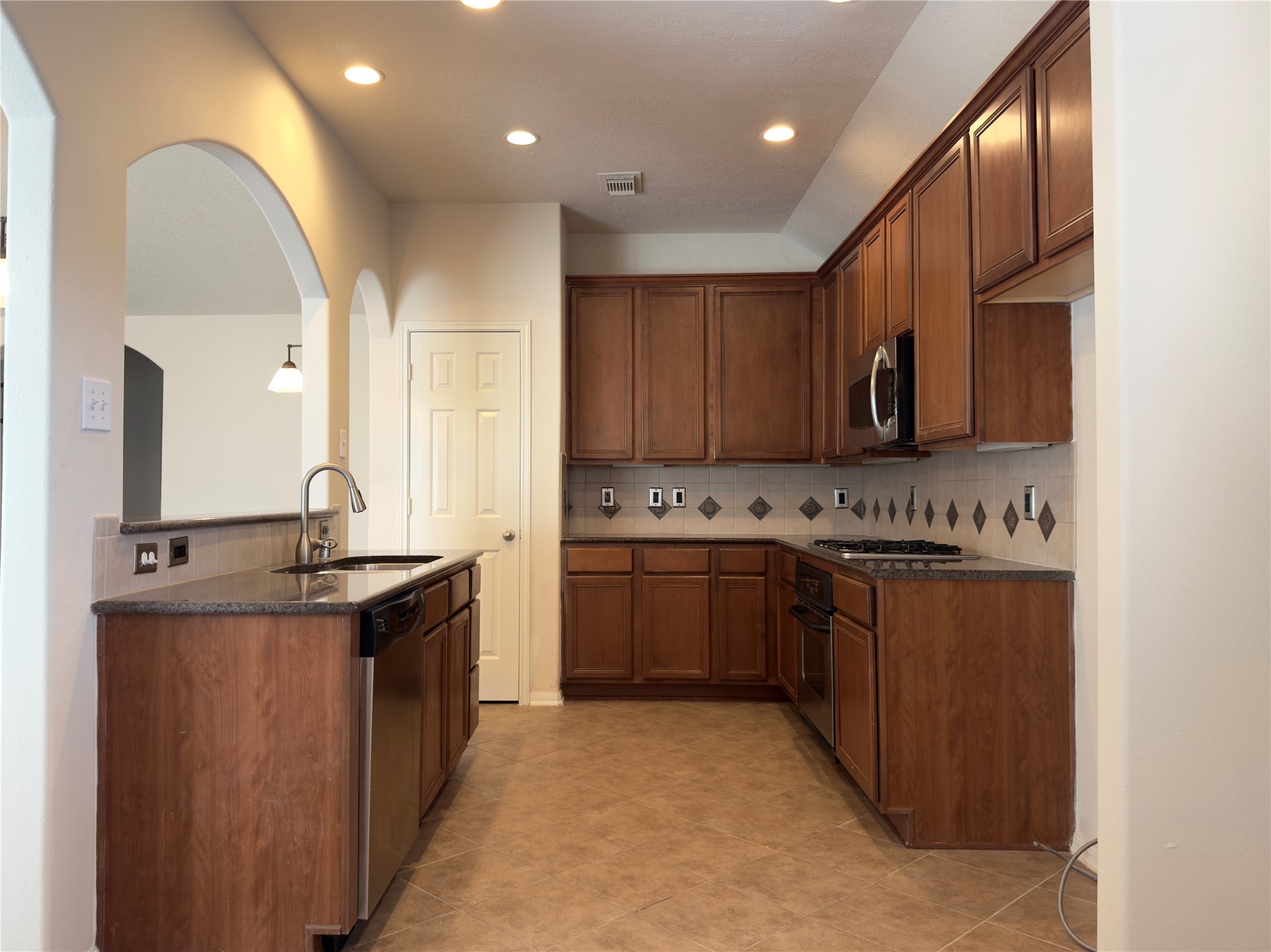 13102 Castlewind Lane Pearland, TX 77584 - Photo 4 of 31 Spacious kitchen with abundant cabinet storage, granite countertops, recessed lighting, and a convenient pass-through opening to the living area.