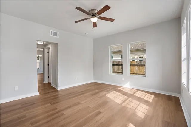 a view of an empty room with window and wooden floor