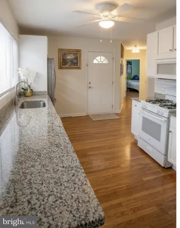 a view of a kitchen with kitchen island a sink wooden floor and a stove top oven