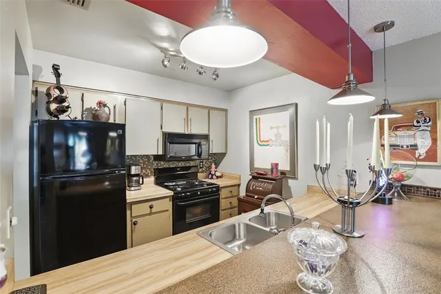 a kitchen with stainless steel appliances granite countertop a refrigerator stove top oven a sink dishwasher and white cabinets with wooden floor